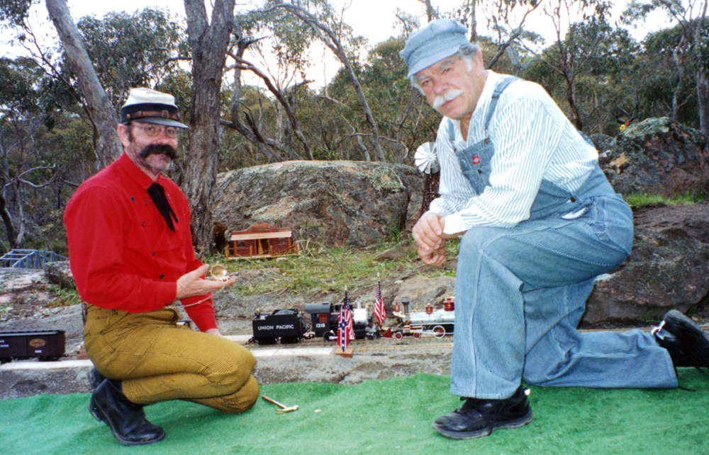 two men kneeling down near garden railway