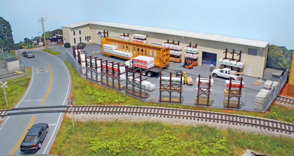 Color photo of a flatcar at lumberyard on an HO scale layout.