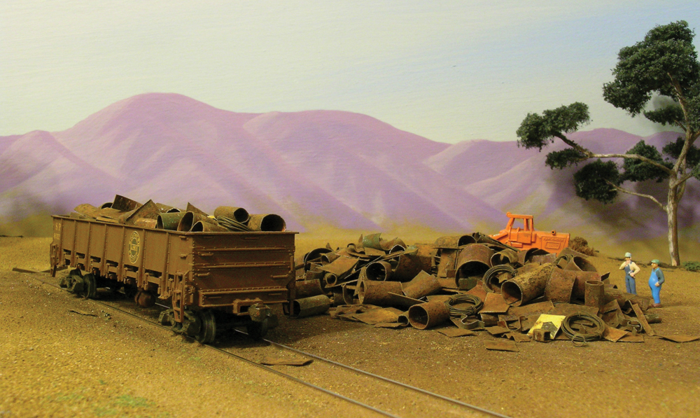 Color photo of HO scale gondola on track next to scrap pile.