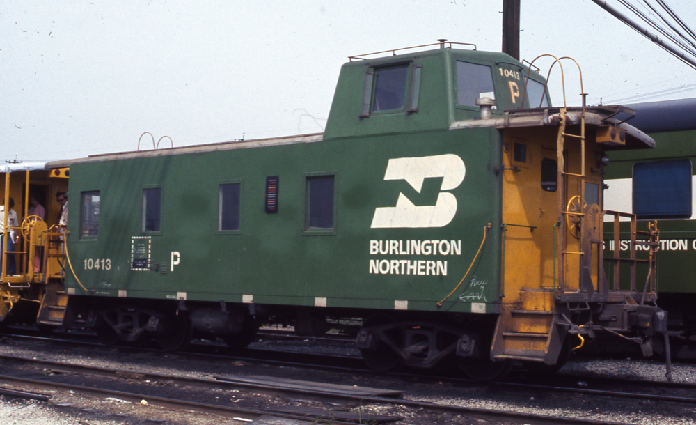 Color photo of steel caboose with streamlined offset cupola.