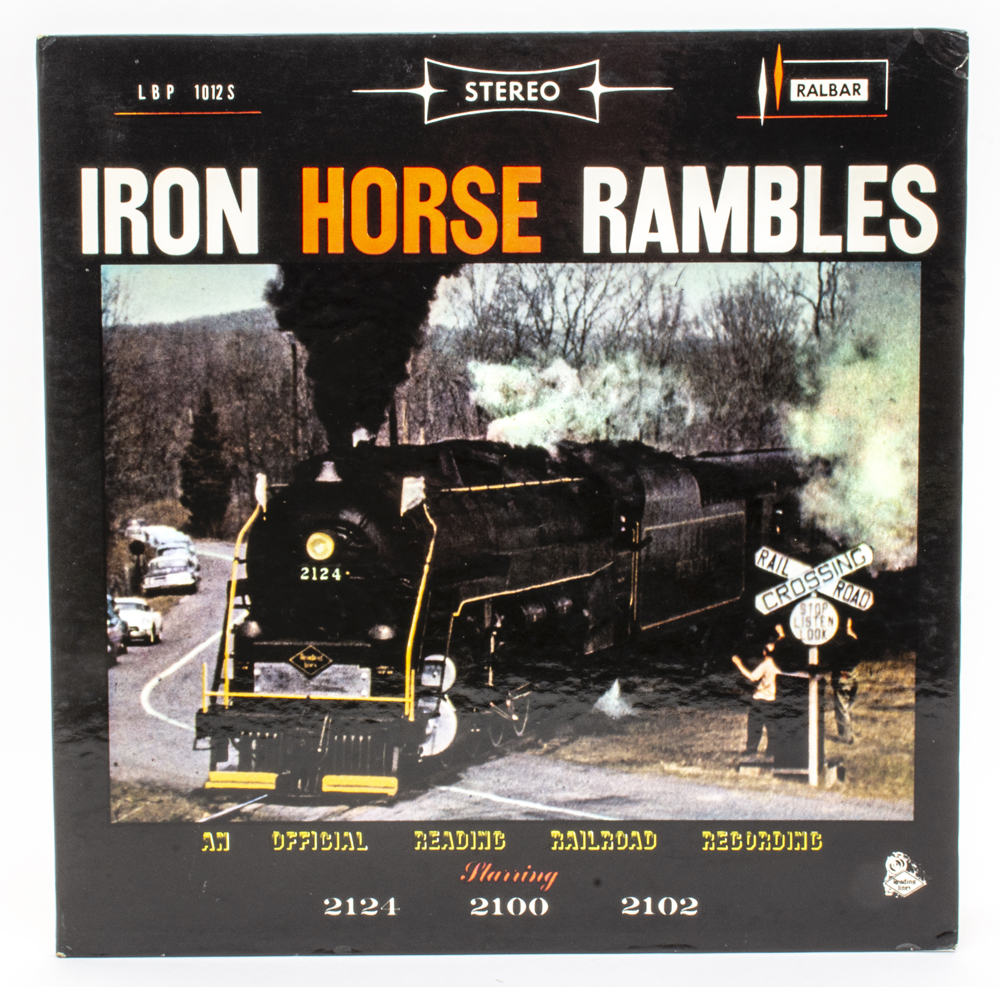 Cover of vinyl record with color photo of steam locomotive rolling through grade crossing.