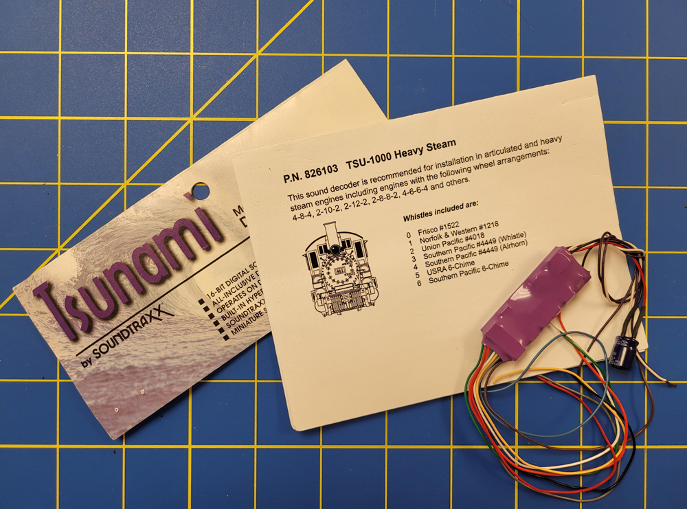 An image of a DCC sound decoder and packaging on a blue background
