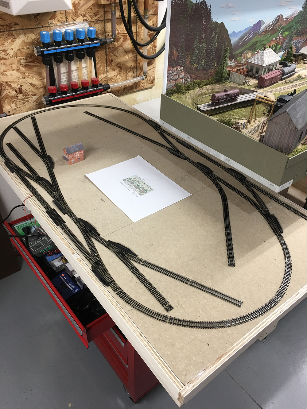 Whiskey Barrel & Grimy Gotham Layout: wood board with black and silver toy train track in a loop on top.