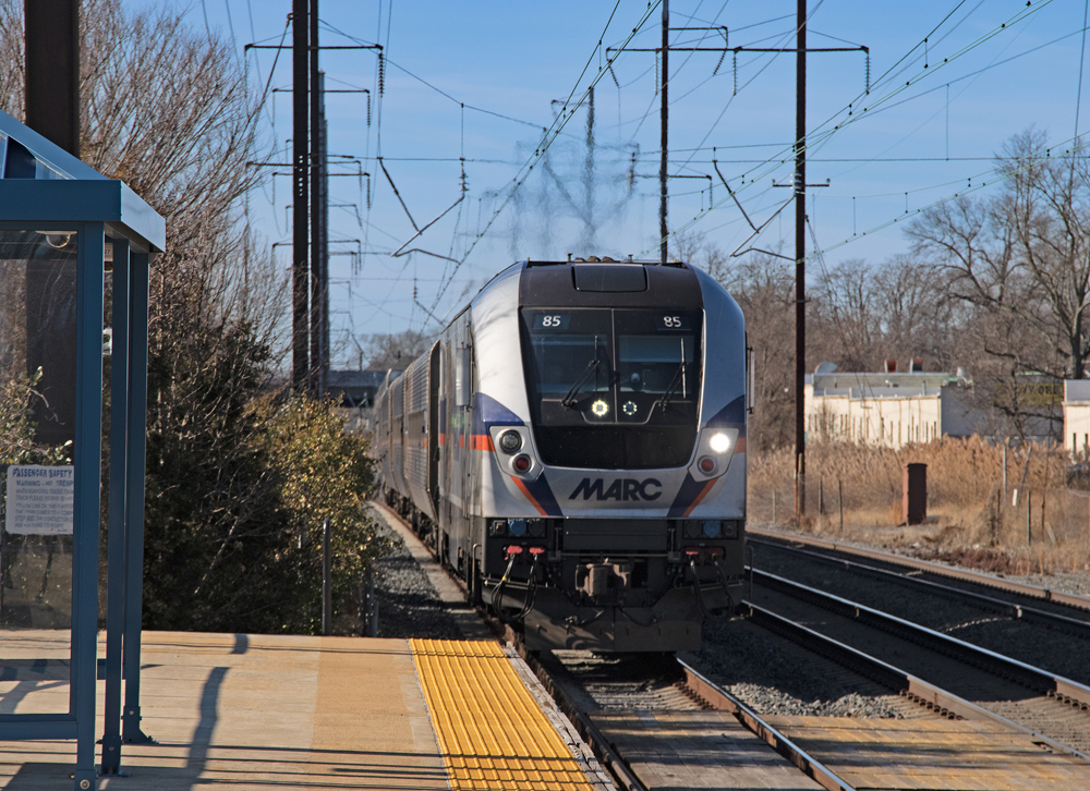 Silver and blue passenger train approaching a station