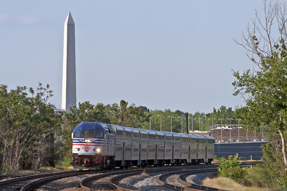 Blue and silver passenger train with Washington Monument in background