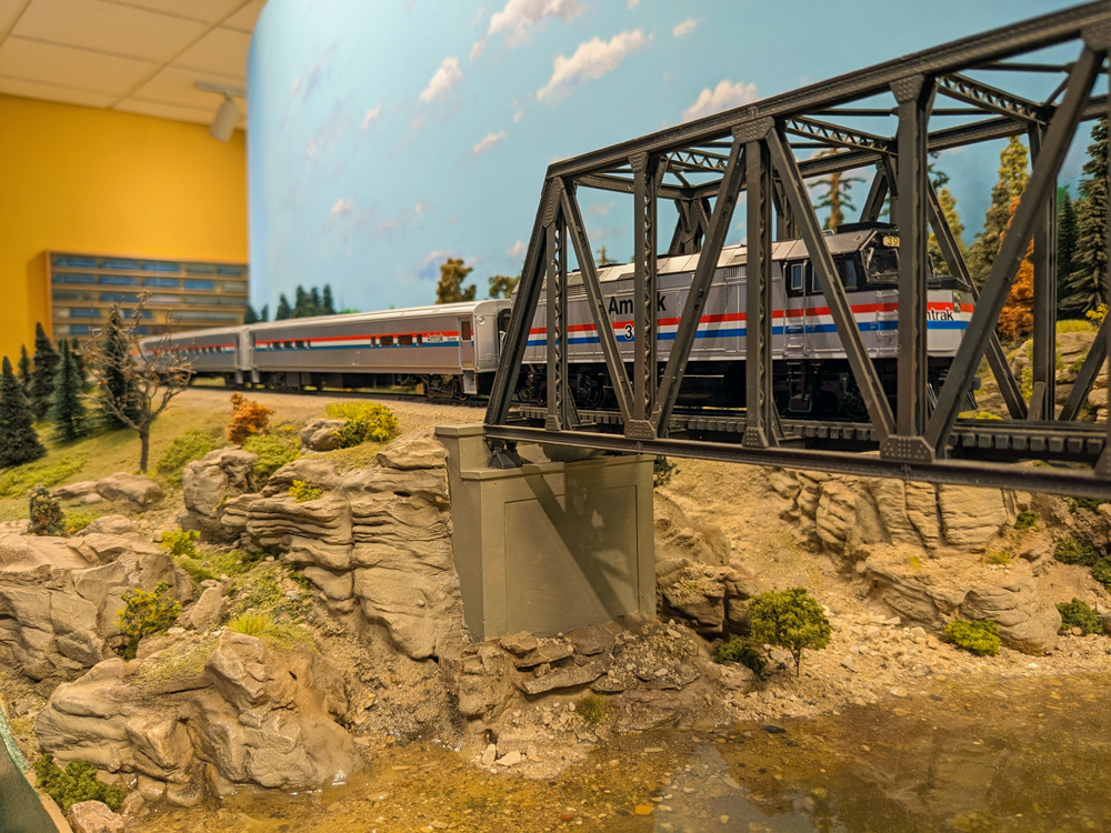 A model passenger train goes through a bridge.