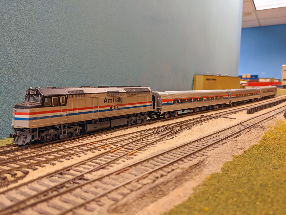 A model passenger train approaches a yard.