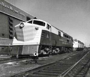 Turbine locomotive in front of shop building.