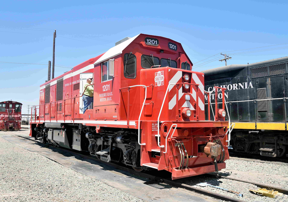 A man looks inside the engine compartment of a red locomotive