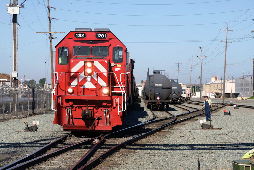 A view of the front of a red diesel locomotive as it switches cars in a railroad yard