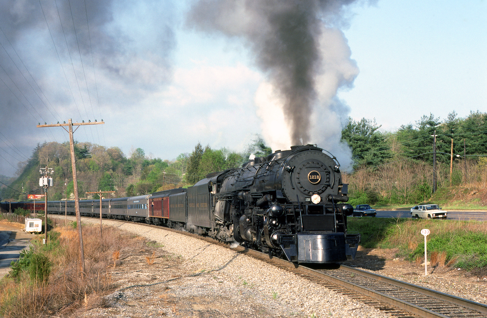 Articulated steam locomotive rounds curve with passenger excursion train
