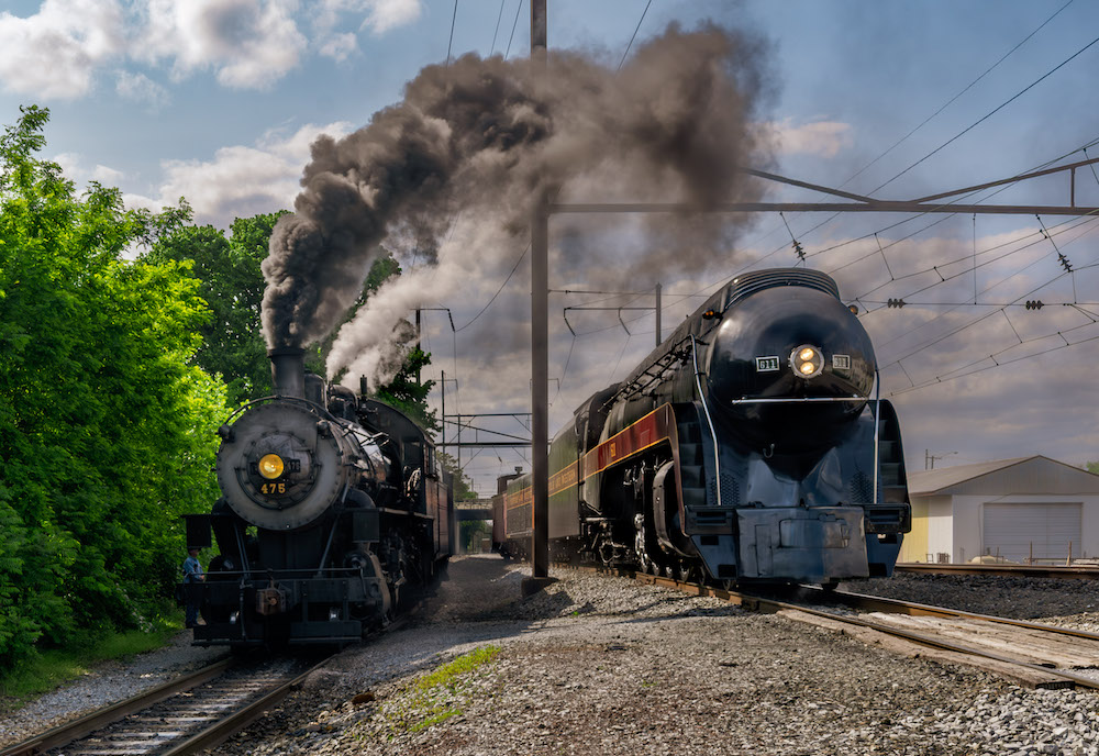 Two steam locomotives sitting side by side.