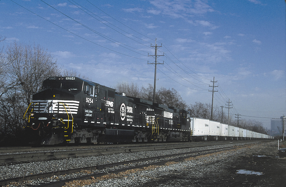 An image of two black locomotives pulling a long train of Triple Crown railcars