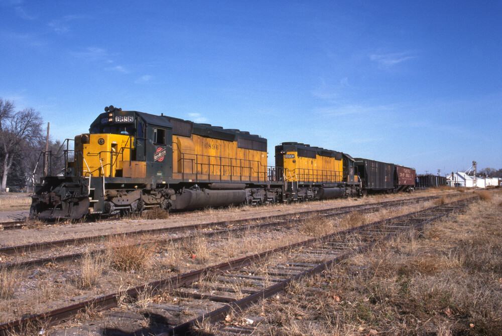 A photograph of two yellow and green SD40-2 diesel locomotives