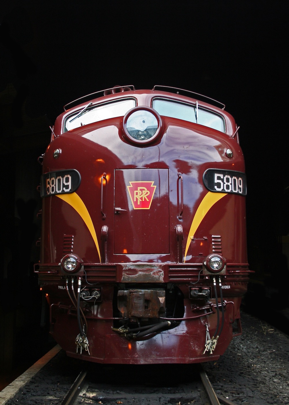 An image of the nose of a red-painted streamlined diesel with gold stripes