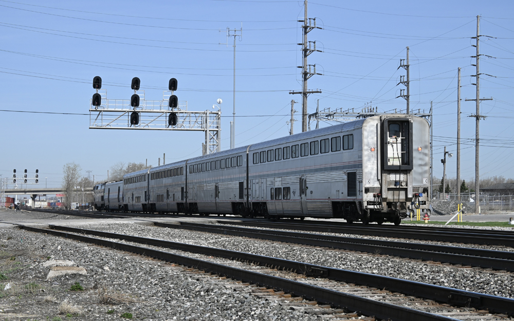 Short passenger train passes under signal bridge