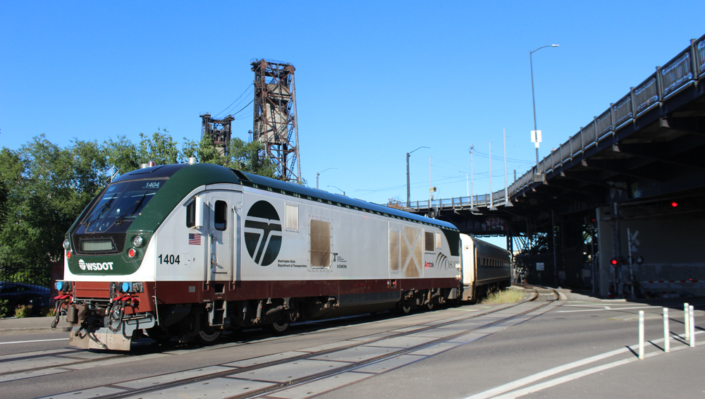White locomotive with green and brown trim on passenger train