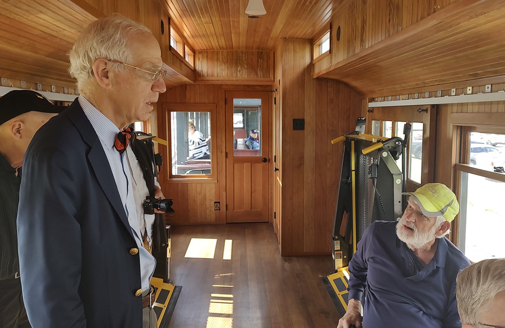 Man standing talking to one seated in passenger car