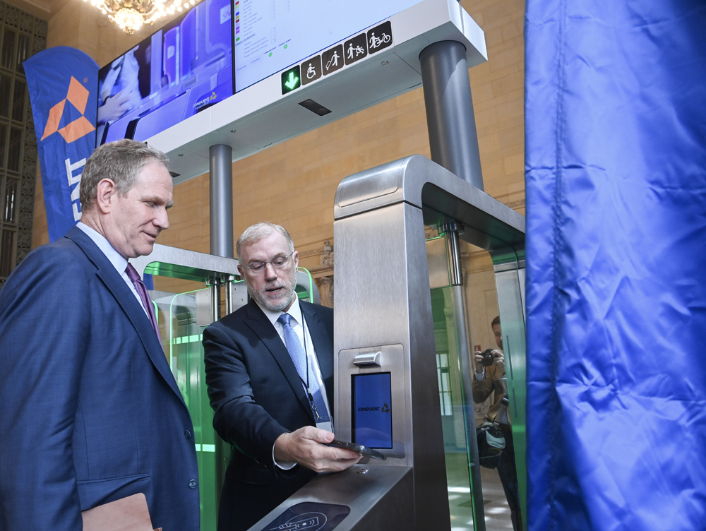 Two men looking at transit turnstile