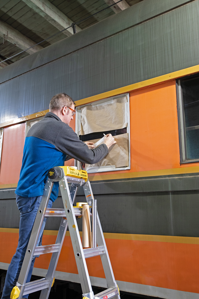 Man working on masking window on passenger car.