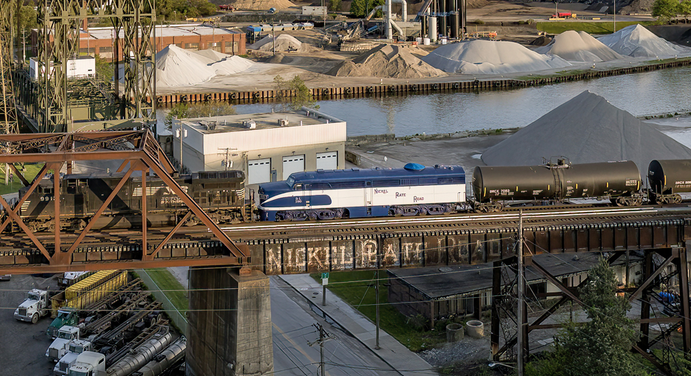 Blue and white streamlined diesel on bridge.