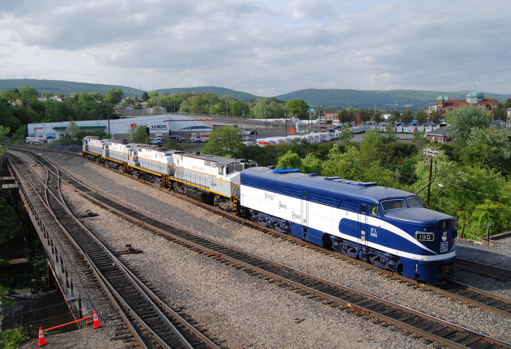 Blue and white locomotive with four gray and white diesels