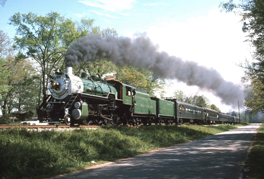Steam locomotive with green paint scheme and passenger cars