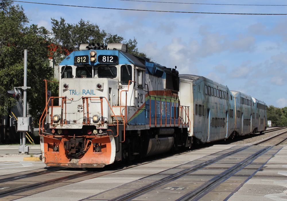 White, orange, and teal locomotive with bilevel passenger cars