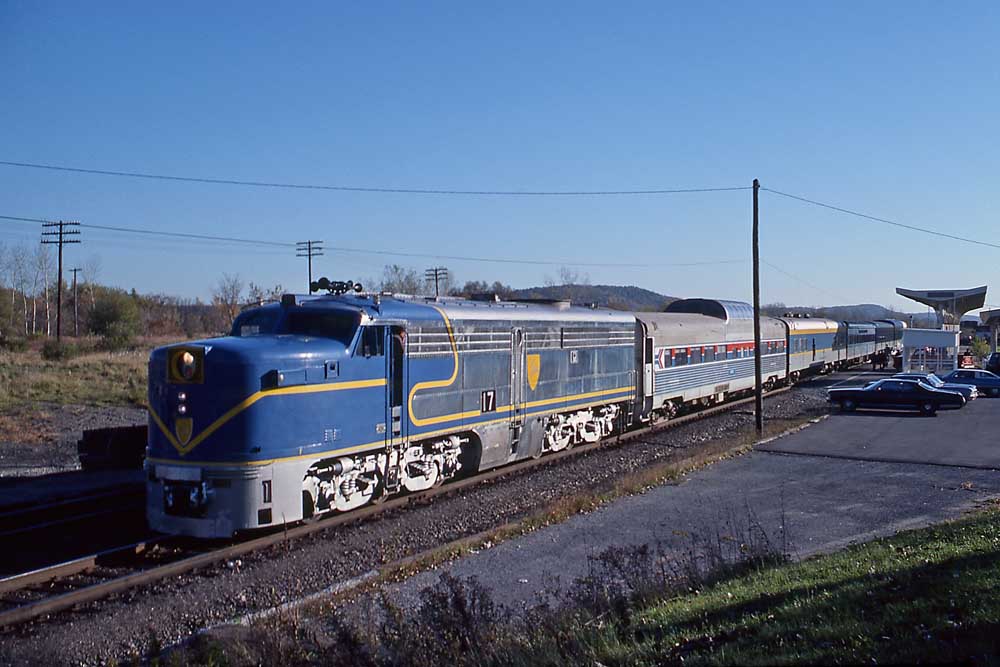 Blue-and-silver diesel locomotive with passenger train at station of Delaware & Hudson history