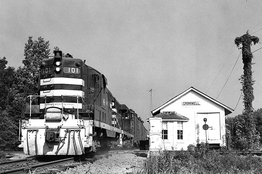 Black Meridian & Bigbee Railroad diesel locomotive passing small wooden station