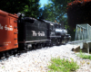 model steam locomotive with two cars head toward bridge on garden railway