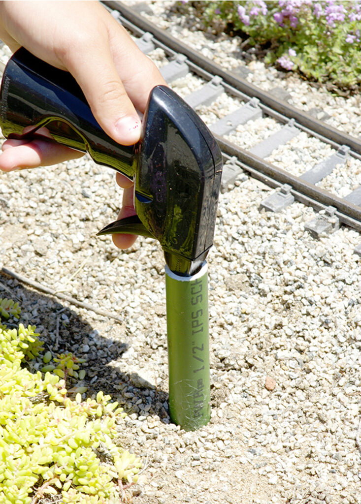 hand holding weed sprayer into piece of PVC pipe