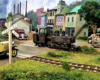 A small tank engine rolls past a bucolic small town