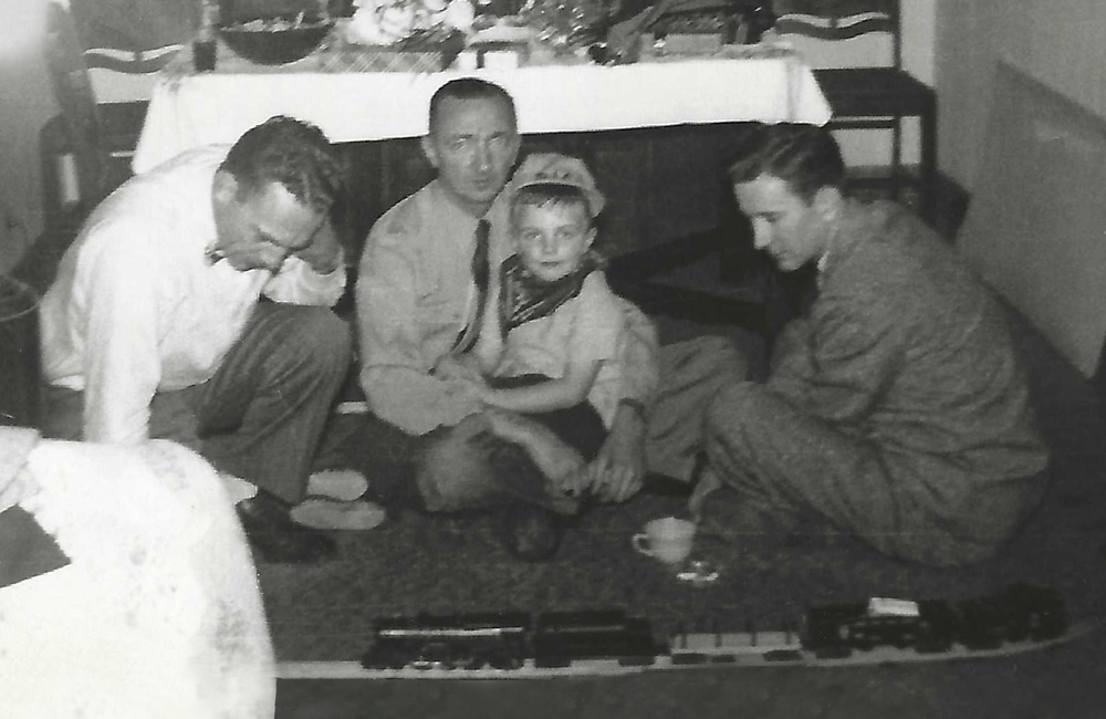 black-and-white photo of three men with boy and toy train