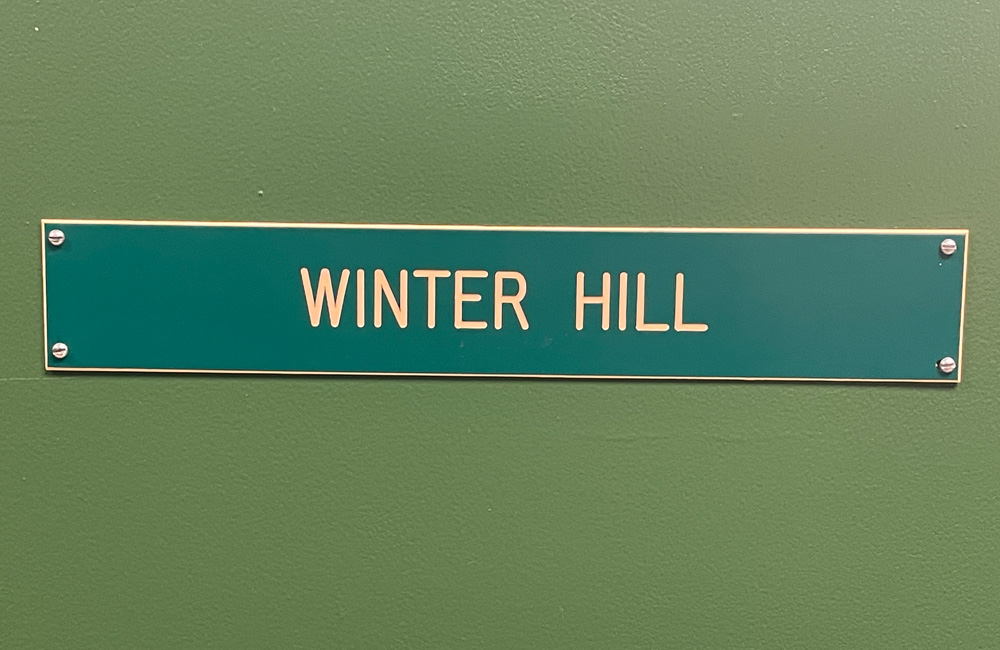A dark green sign reading WINTER HILL on a green background