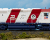Color image of red, white, and blue HO scale diesel on scenic base.