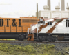 Color photo of two HO scale locomotives on scenic base with industrial backdrop.