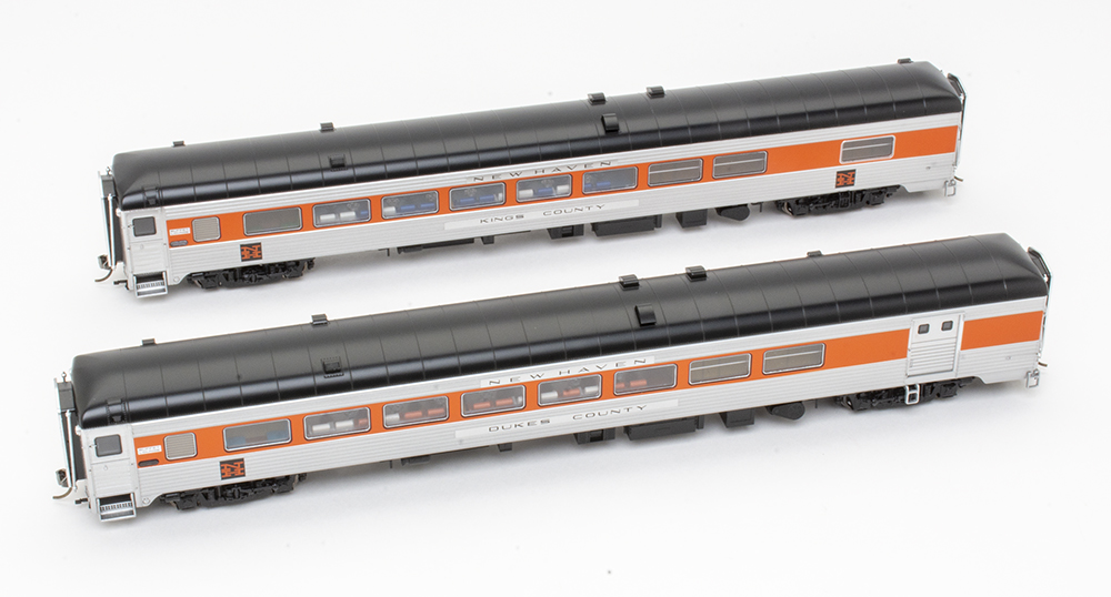 Rapido new haven county cars: A rooftop view of two orange, silver, and black model train passenger cars positioned side by side