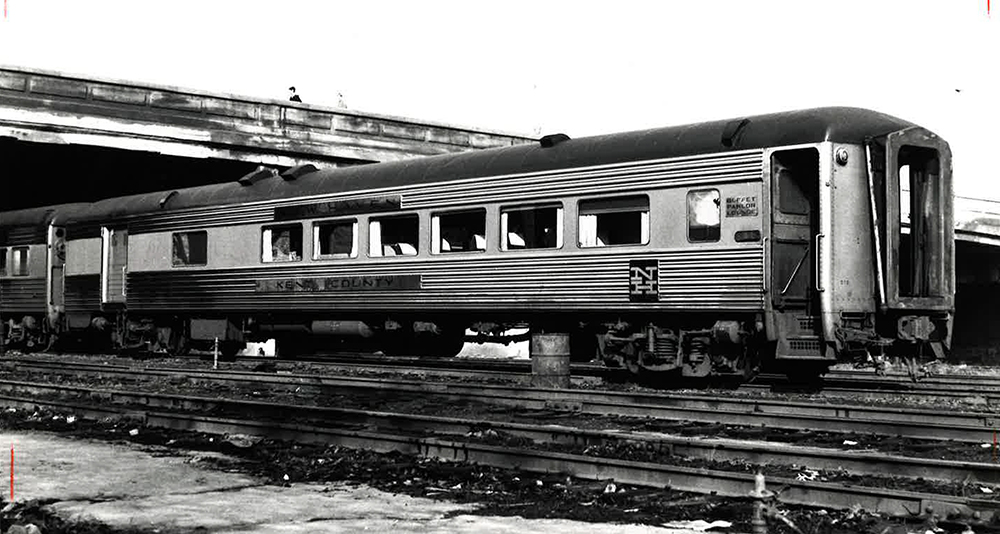 Black and white photograph showing a dirty gray train car with a large doorway at one end used for baggage.