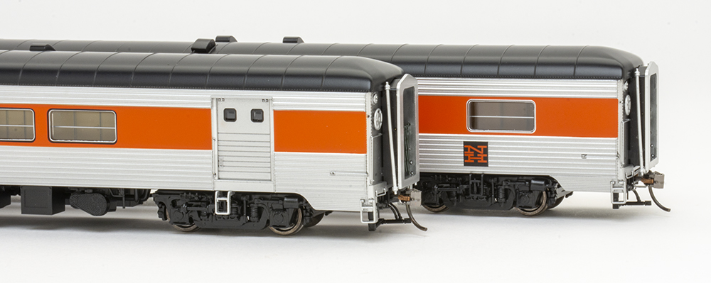 Rapido new haven county cars: Orange, silver, and black model train passenger cars showing silver baggage door with two small windows.