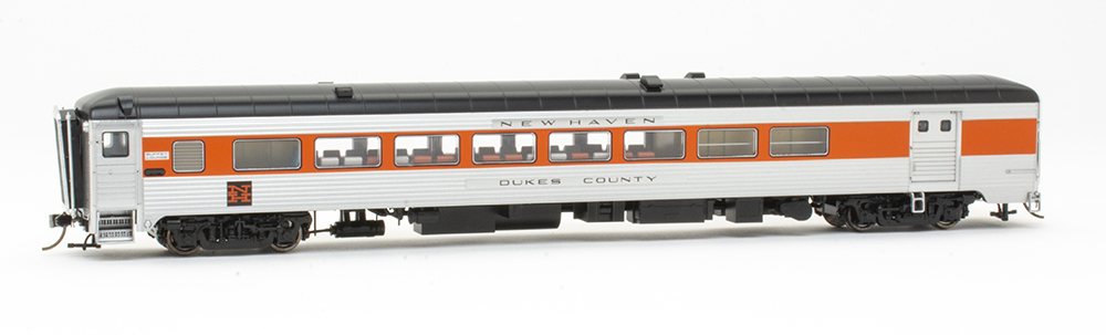 Rapido new haven county cars: Side view of an orange, silver, and black model train passenger car featuring windows and a large silver door.