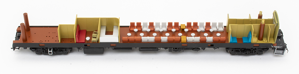 Model train passenger car with shell removed, revealing small maroon and tan chairs and brown walls.