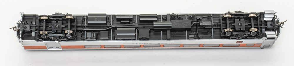 Black and gray boxes and pipes on the underside of a model train passenger car