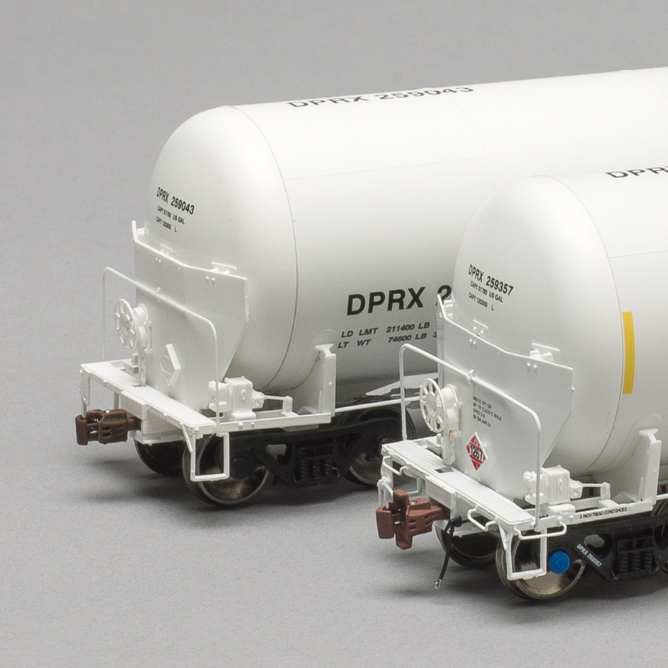 Color photo of two HO scale tank cars on gray background. 