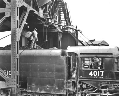 Cab and tender of a large black steam locomotive. Coal is being loaded into the tender. More of the Big Boy story