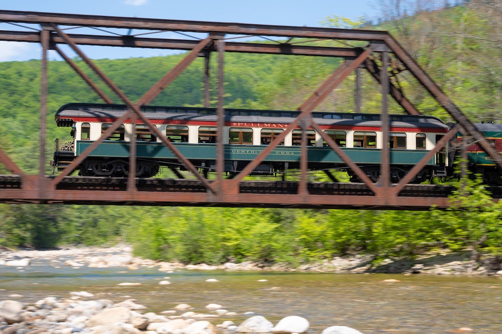 Observation rail car crossing a bridge over rushing water