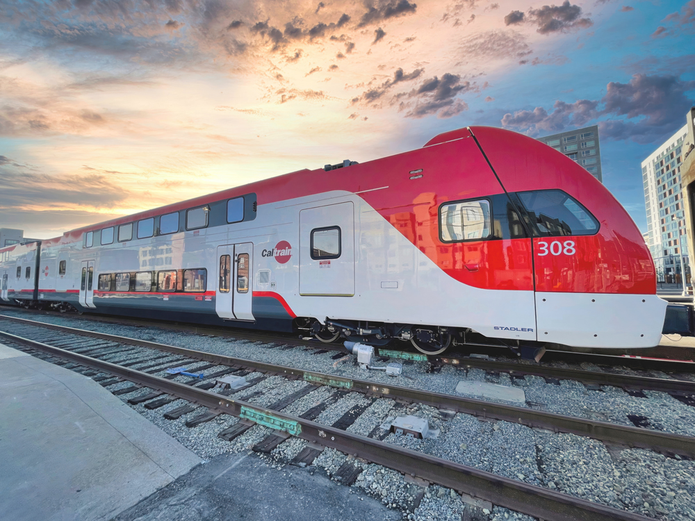 Red and white electric multiple-unit trainset under dramatic sunset