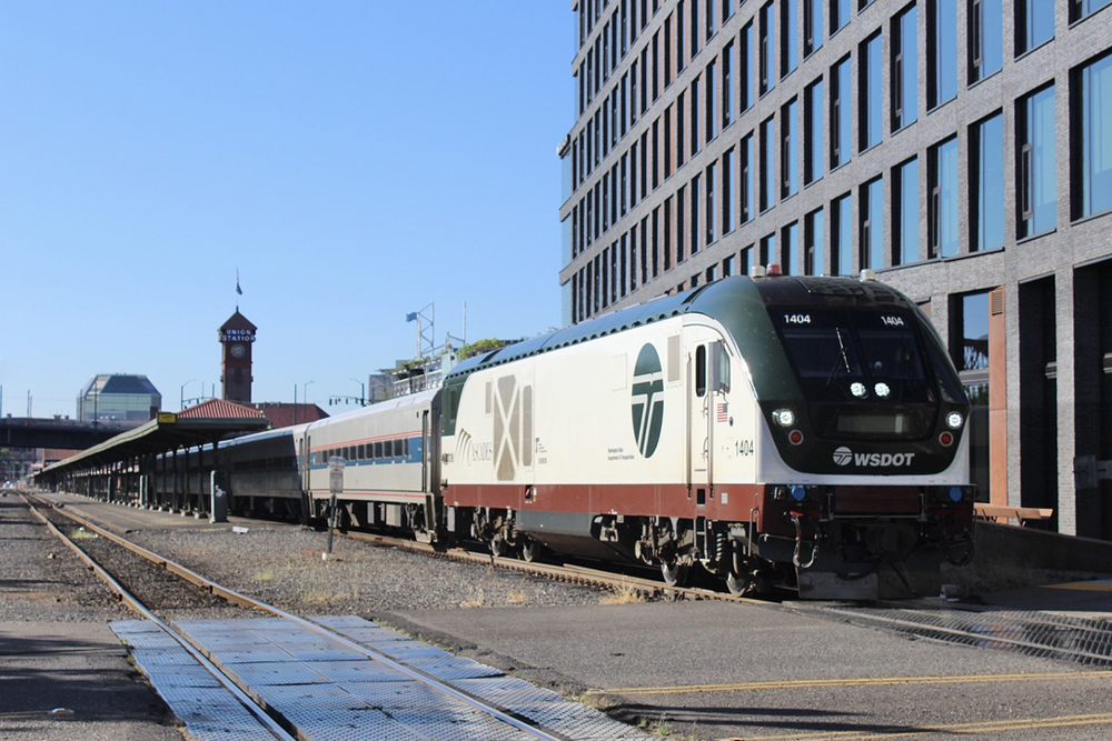 Passenger train with white, green and brown locomotive at station