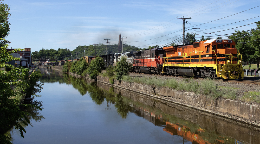 Three locomotives lead train reflected in water