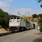 Commuter train with white locomotive emerges from tunnel